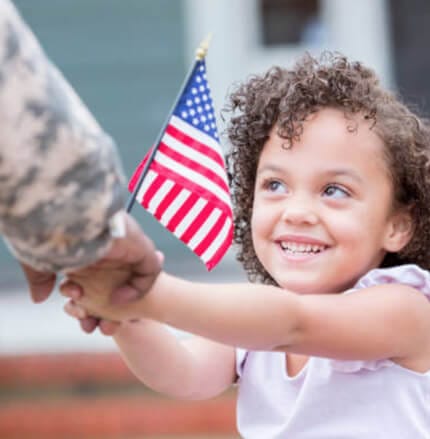 Child handing flag to servicemember
